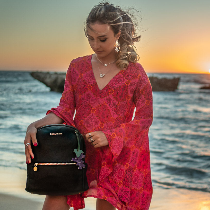 夕日の海辺でバッグを持つ女性の写真